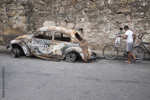Scene at the entrance to the Vidigal favela in Rio de Janeiro features an old burned out ruined fusca car