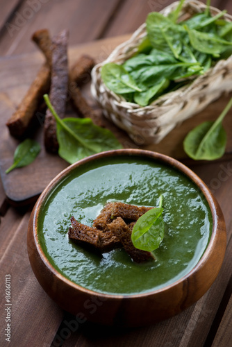 Spinach cream-soup with croutons in a wooden bowl, vertical shot
