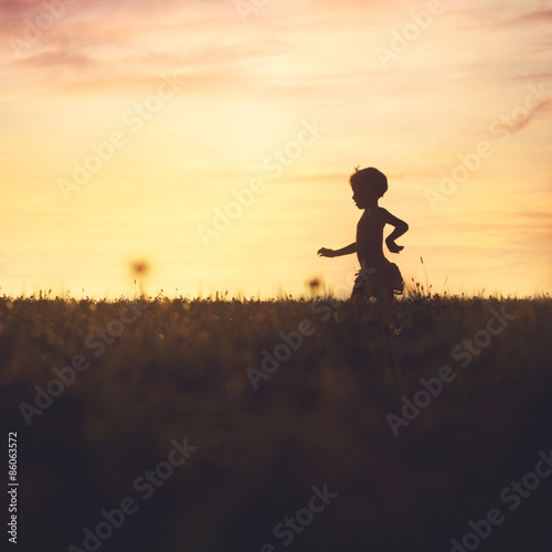 carefree baby running in the field at sunset