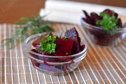 Fresh sliced beetroot salad with onion and parsley on a glass bowl