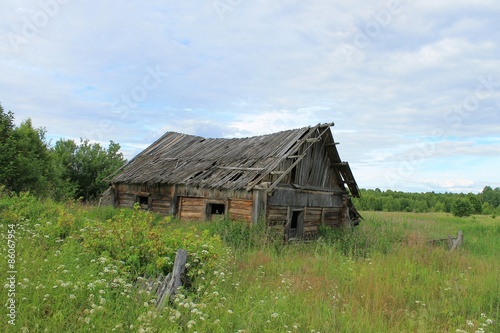 Разрушенный дом в заброшенной деревне на поле летом
