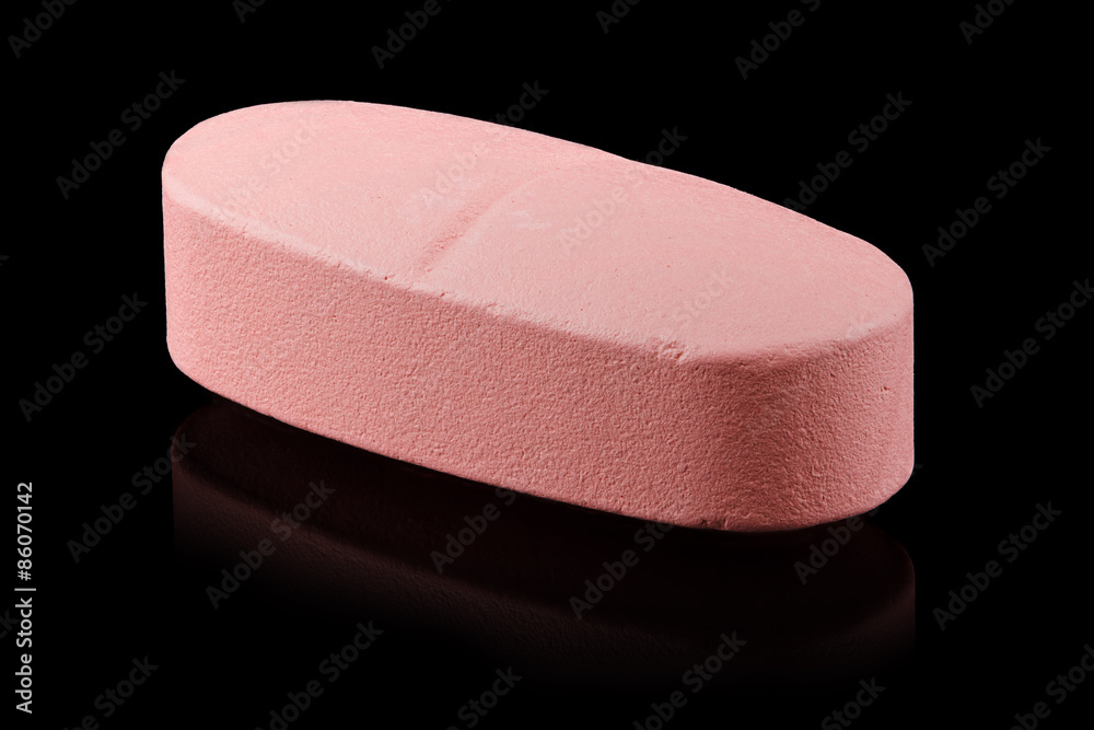 One pink pill isolated on black background. One pink pill isolated on black background.