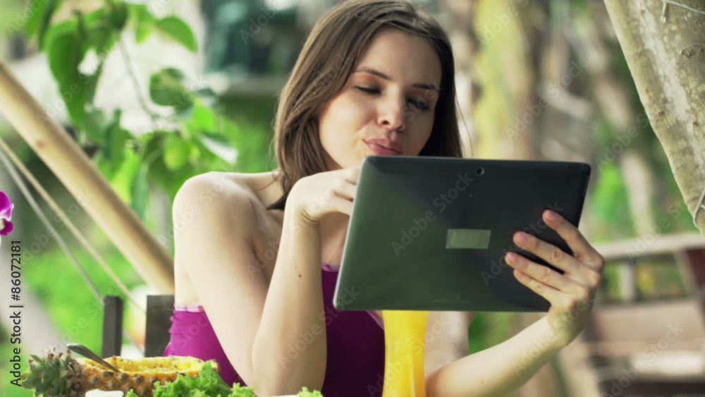 Young woman with tablet computer drinking cocktail sitting in exotic cafe
Young woman with tablet computer drinking cocktail sitting in exotic cafe