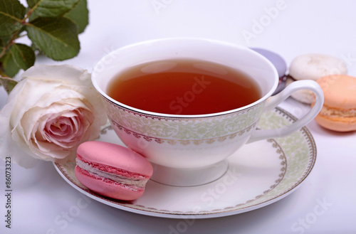 Cup of tea with pink french macaron and pastel rose