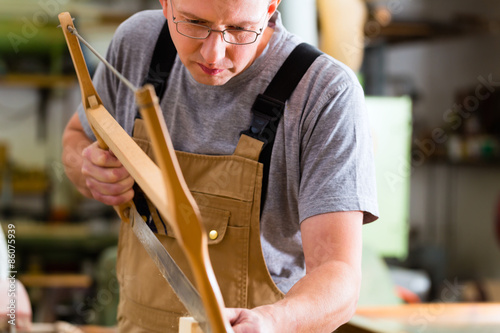 Tischler oder Schreiner arbeitet mit einer Handsäge in einer Tischlerei oder einer Werkstatt