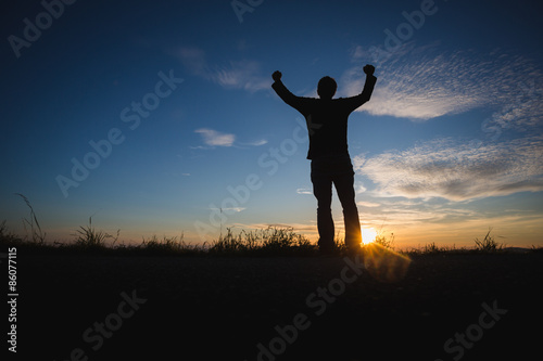 silhouetted man standing in sunset sky