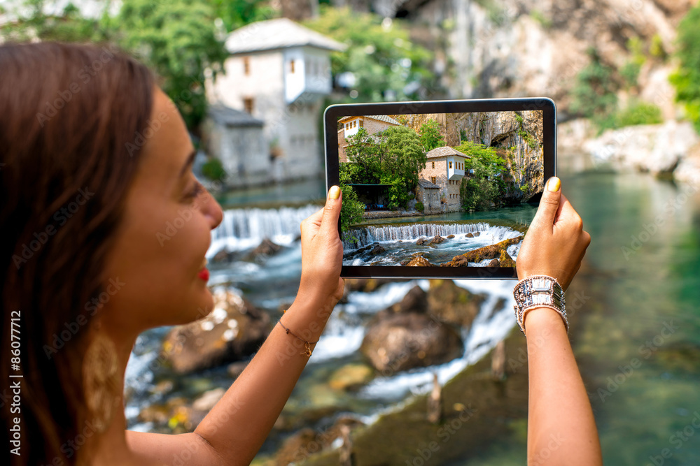 Woman photographing house on Buna spring in Blagaj village