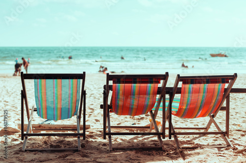 Vintage toned three beach chairs on tropical shore