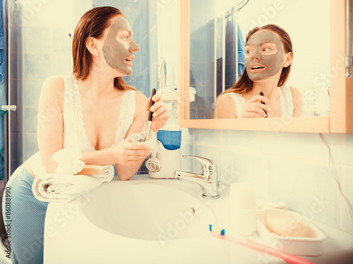 Woman applying mud facial mask