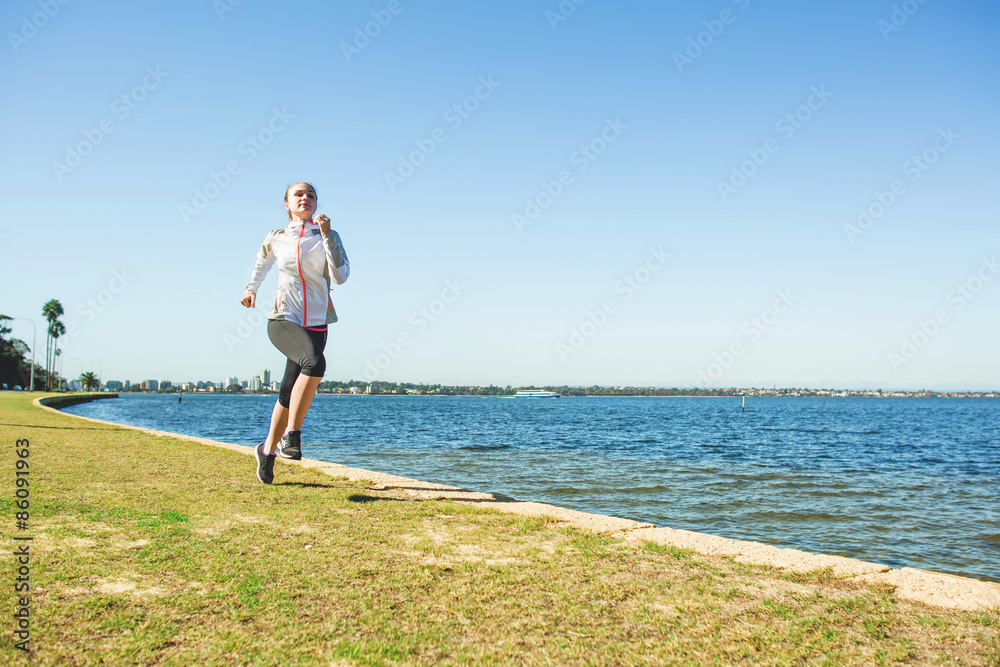 Young woman running near the river at sunny day. Sportswoman