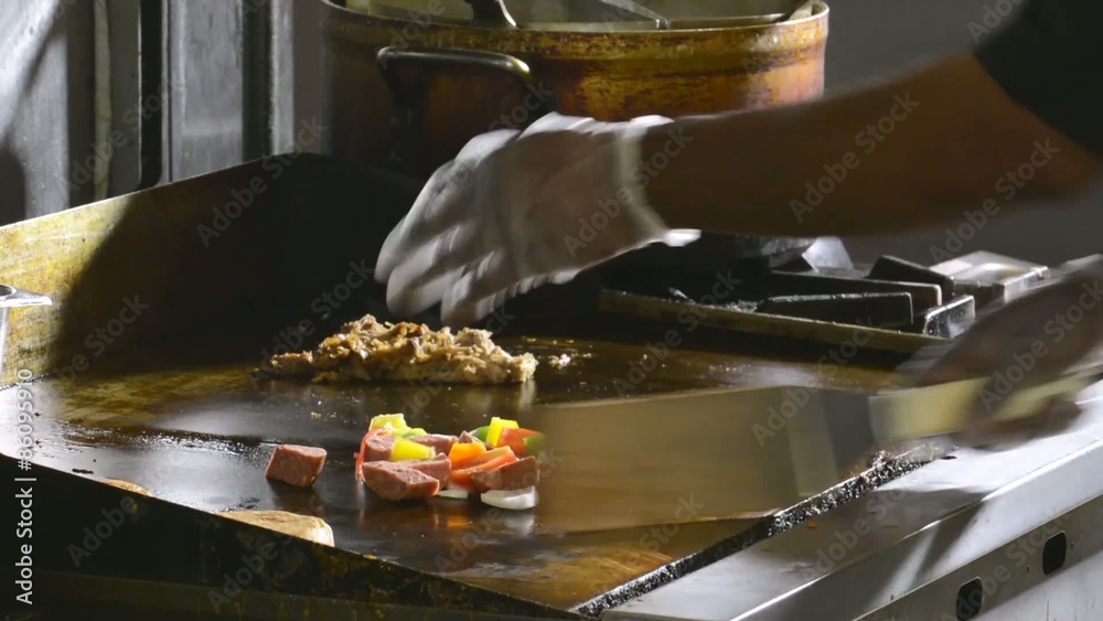 Chef adding food to a grill
