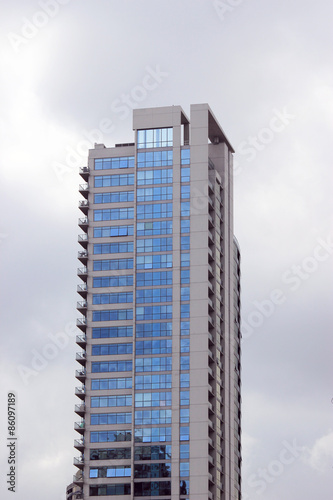 Residential building with blue windows on cloudy sky background