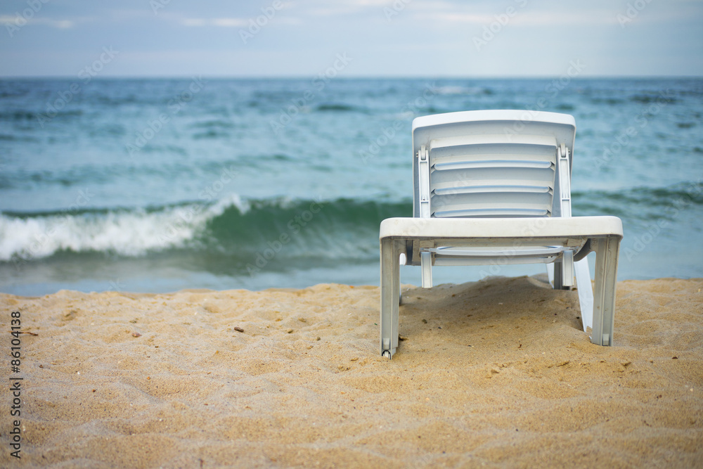 Plastic white lounge chair on empty beach