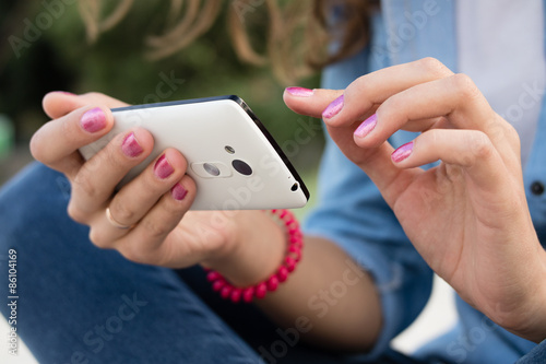 Women's hands with red manicure holding a modern mobile phone wi
