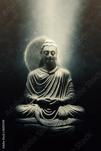 Statue of a seated Buddha lit by a beam of light