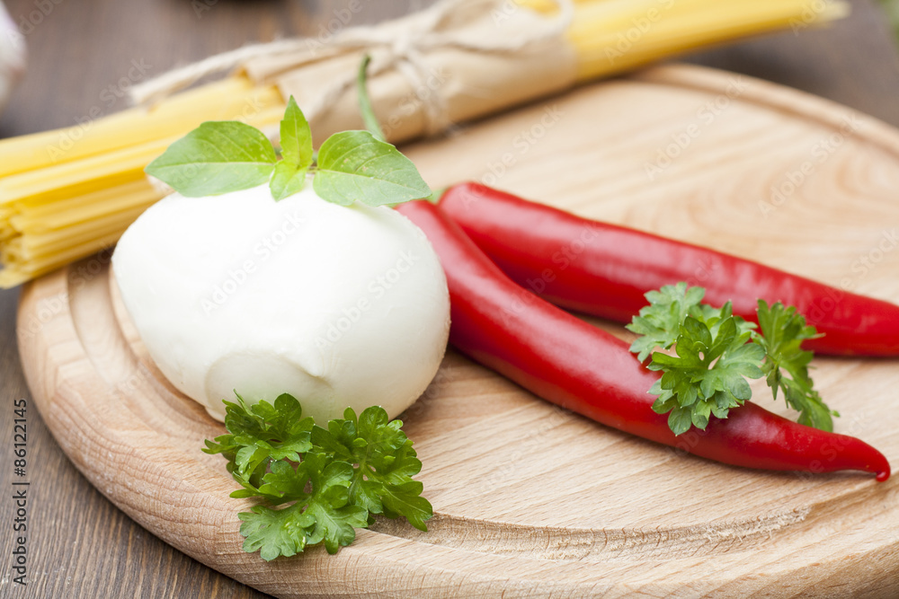 Mozzarella with herbs, noodles, chilli, on a wooden round board, selective focus Mozzarella with herbs, noodles, chilli, on a wooden round board, selective focus