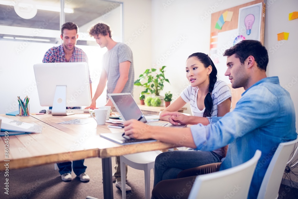 Creative business team gathered around laptops Creative business team gathered around laptops