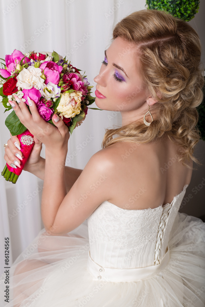 beautiful gentle young girl happy bride in a white dress sitting on a chair and smelling a bridal bouquet with a nice manicure
