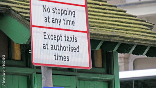 No Red Route sign on the street of London. It means no stopping anytime on that area