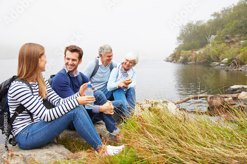 A senior and a young adult couple sitting together by a lake