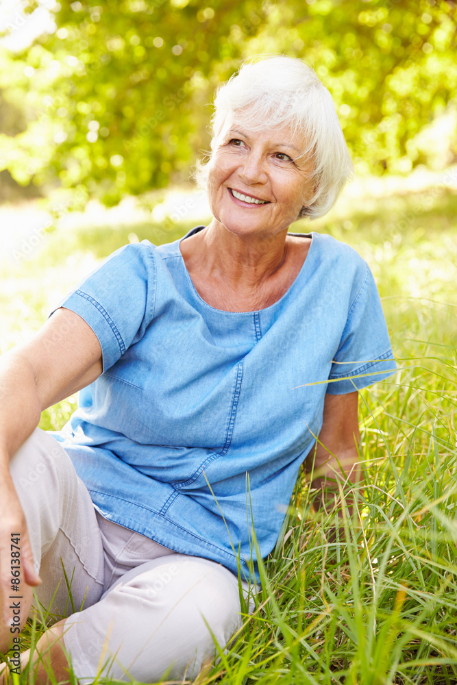 Senior woman sitting on grass relaxing Senior woman sitting on grass relaxing