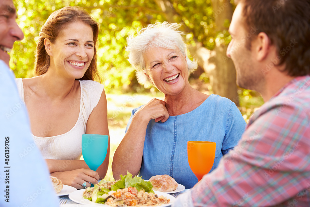 A senior and a young adult couple eating together outdoors