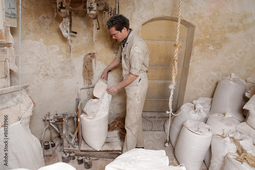 miller puts flour in a bag to weigh it on a balance in the mill photo