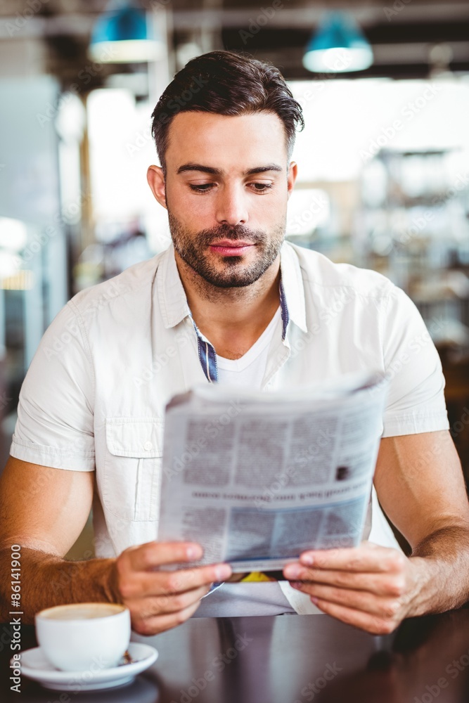 Young man having cup of coffee reading newspaper Young man having cup of coffee reading newspaper