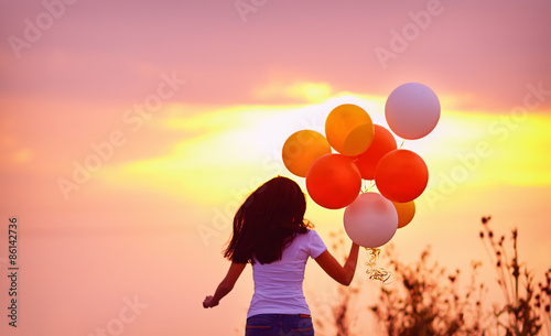 young woman with air balloons running summer field , on sunset