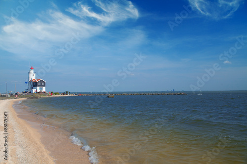 lonely lighthouse stands on the spit in the sea near the village