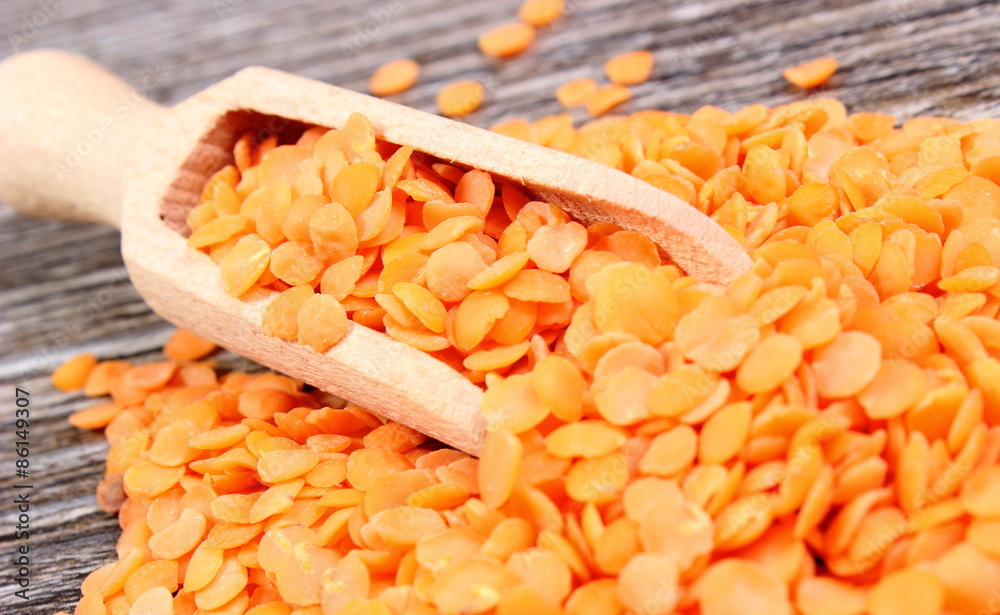 Heap of red lentil with spoon on wooden background Heap of red lentil with spoon on wooden background
