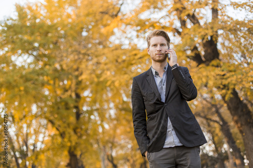 Young man with mobile phone in the autumn park