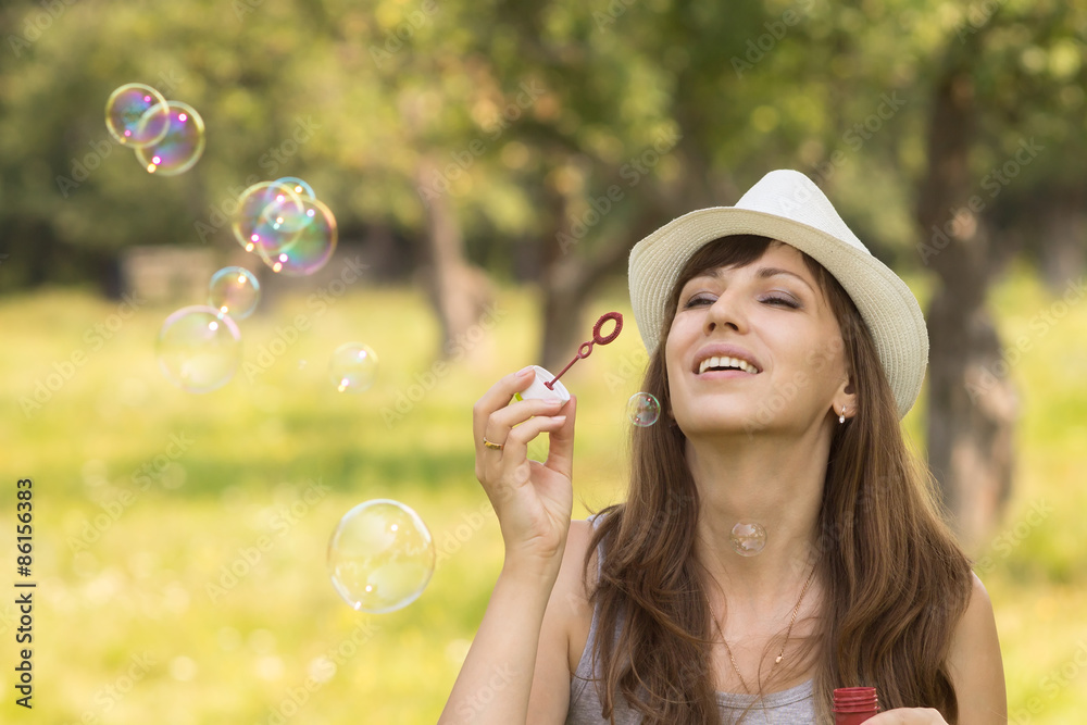 Young pretty caucasian woman having fun with blowing bubbles