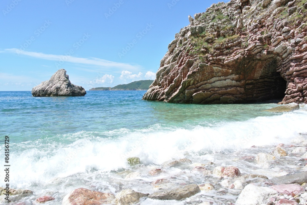 Summer coastal landscape - rocky beach and transparent turquoise sea, with waves crashing on the shore, on a sunny summer day. Summer coastal landscape - rocky beach and transparent turquoise sea, with waves crashing on the shore, on a sunny summer day.