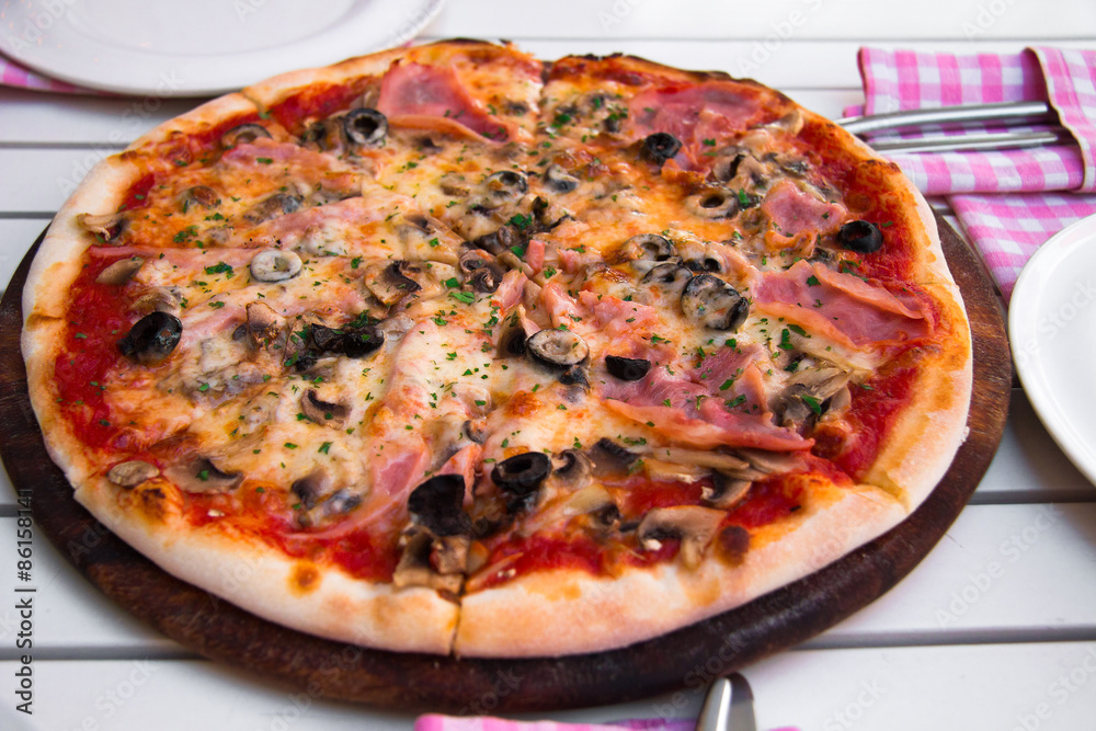 Italian delicious hot pizza on wooden plate, on white table