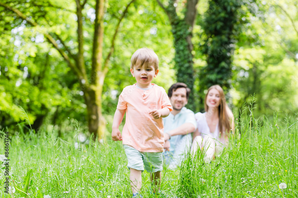 Junge rennt und spielt auf Wiese mit der Familie Junge rennt und spielt auf Wiese mit der Familie
