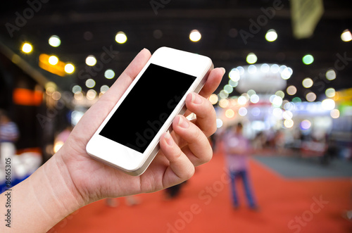 woman hand holding the phone tablet on blur event background