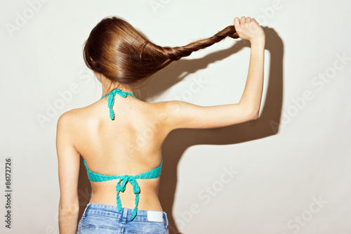 Rear view of young woman in bikini top holding her hair