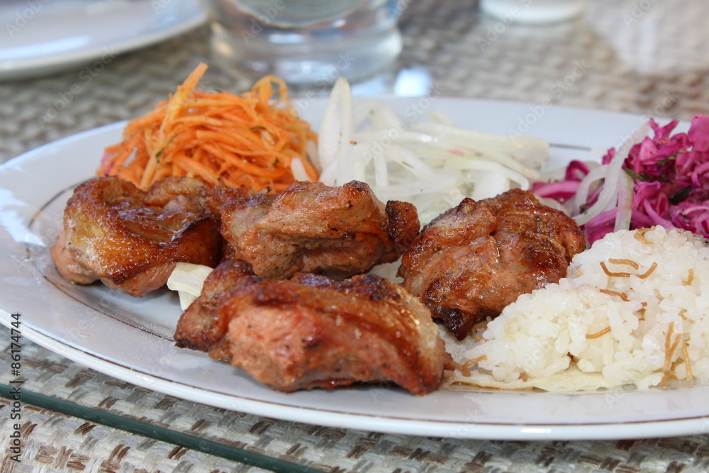 Grilled meat.
Fresh portion of shish kebab on plate with onion and greens.