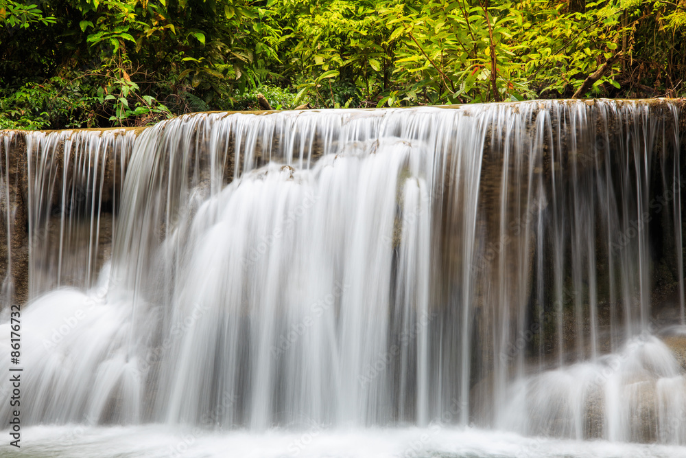 Obraz premium Water flowing over rocks in waterfall cascade in a forest
