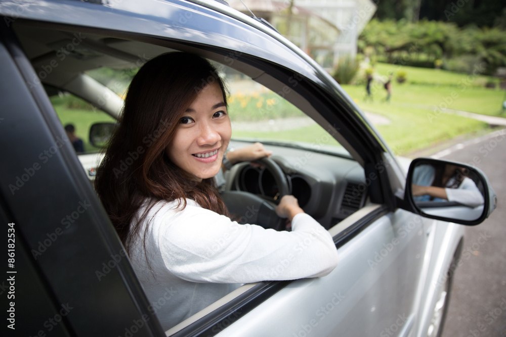 Happy young asian woman riding a car