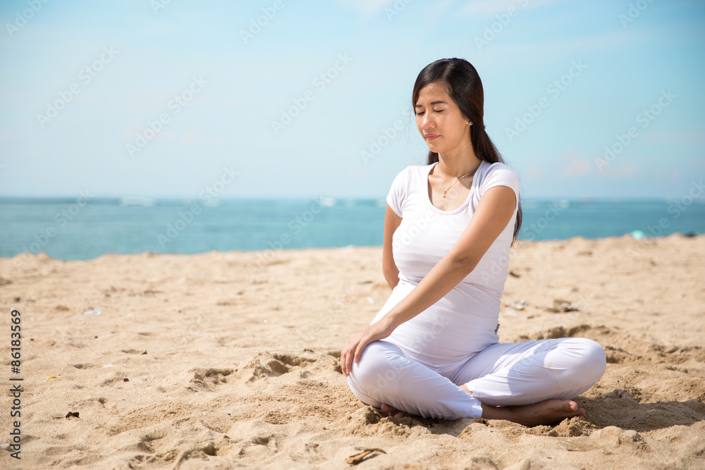 Pregnant asian woman doing yoga in the sea shore
