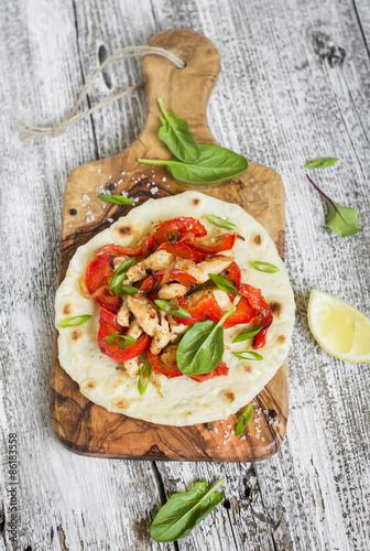 chicken breast, roasted red peppers and onions and homemade tortilla on a light wooden background