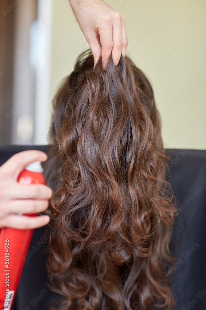 Naklejka premium stylist with hair spray making hairdo at salon