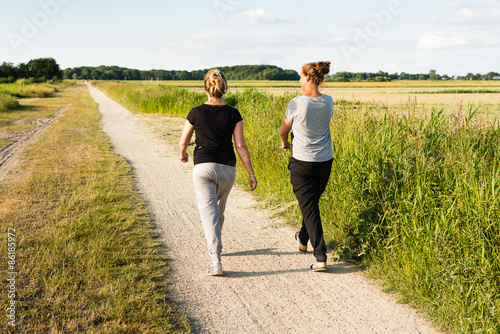 Two women walking on sandy path photo