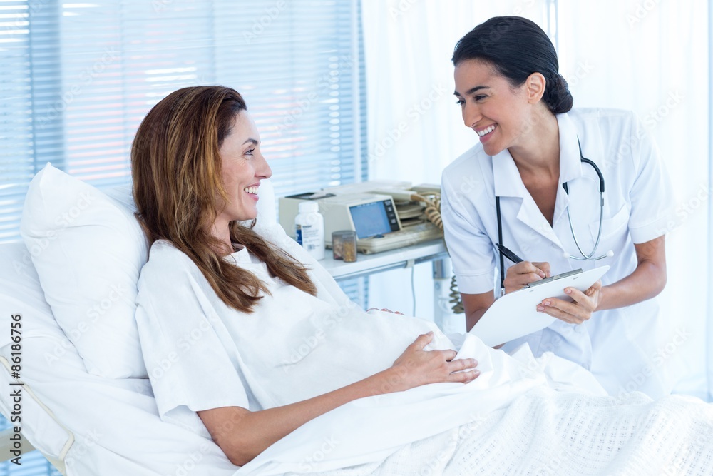 Fototapeta premium Smiling pregnant woman with her doctor