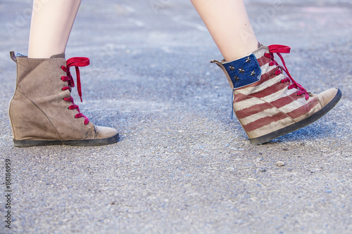 Female legs in sneakers with the design of the American flag on