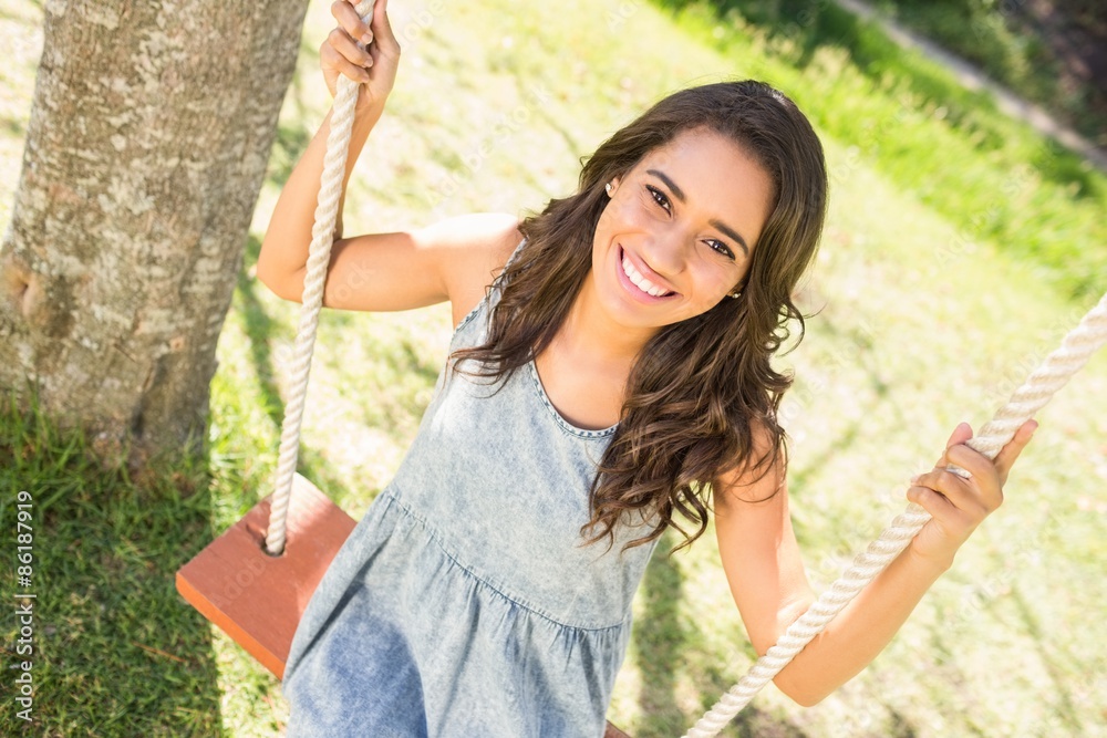 Naklejka premium Pretty brunette swinging in park 