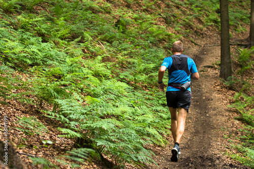 man running and training on the single trail in the forest