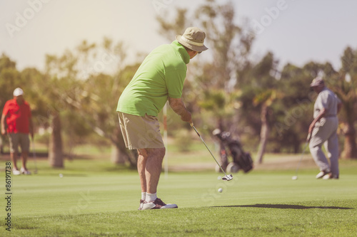 Senior golf player putting on the green. Vintage tone photograph